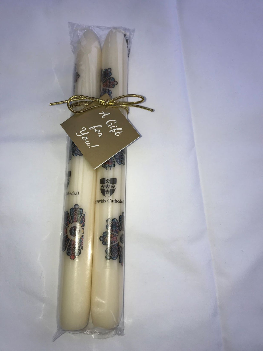 Pair of stick candles with St Davids Cathedral Shield and a picture of the Rose Windows